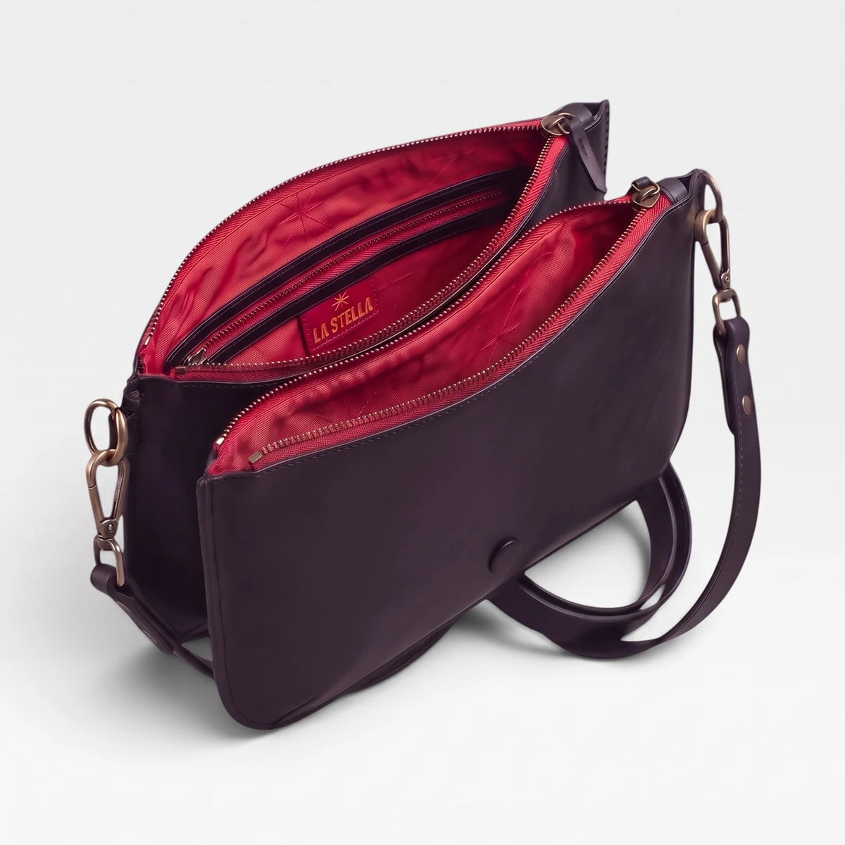 Base Baby Double en cuir prune ouverte, ses deux compartiments zippés doublés de rouge, bandoulière détachée